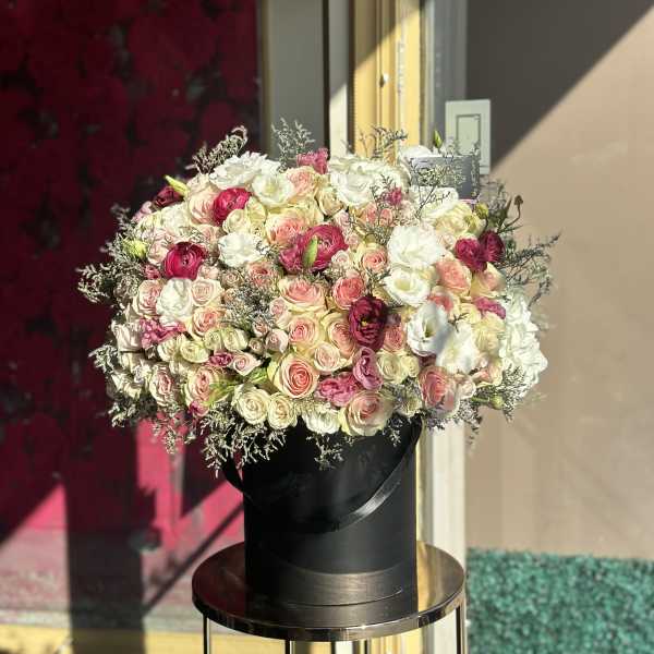 Large bouquet of pink, white, and cream roses in a black hat box