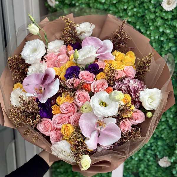 Bouquet of pink, yellow, white, and purple flowers wrapped in brown paper