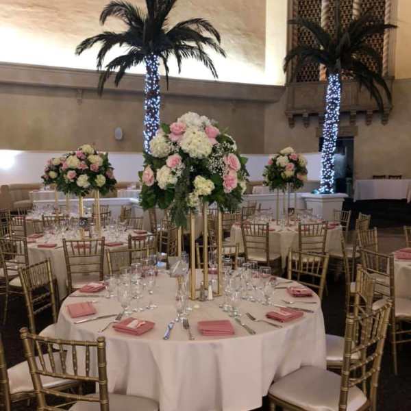 Tall floral centerpieces on round banquet tables in a reception hall