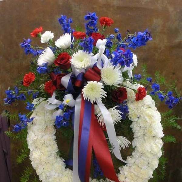 Standing floral wreath with red, white, and blue flowers on an easel