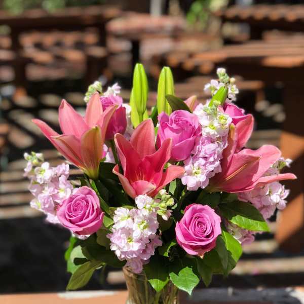 Pink roses and lilies arranged in a clear glass vase