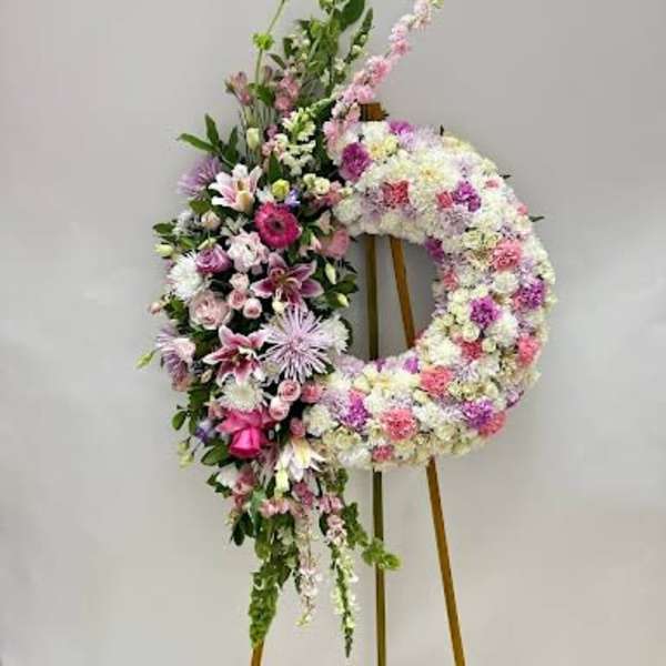Floral standing wreath on an easel with pink, white, and purple flowers