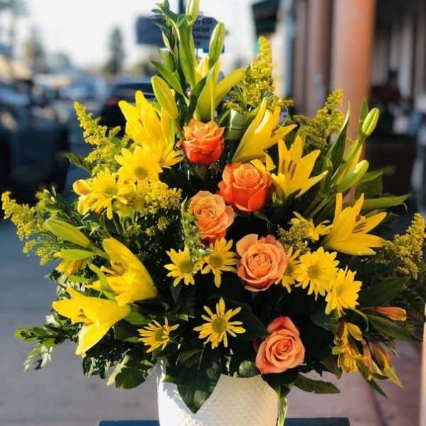 Yellow lilies and orange roses in a white vase