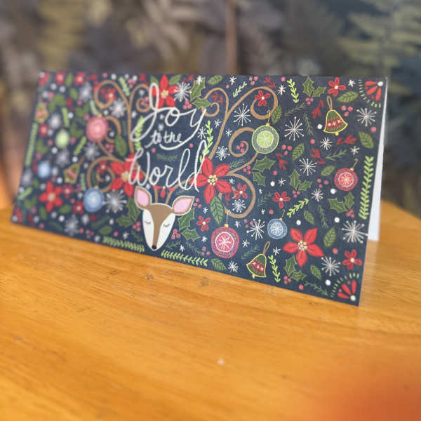 Holiday card with a deer and "Joy to the World" text