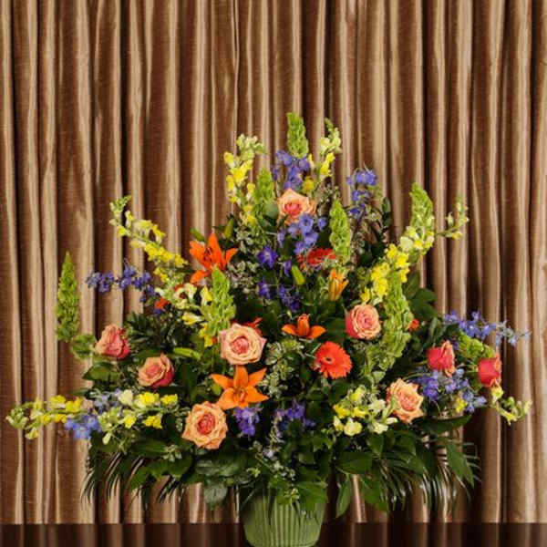Large mixed flower arrangement in a green vase