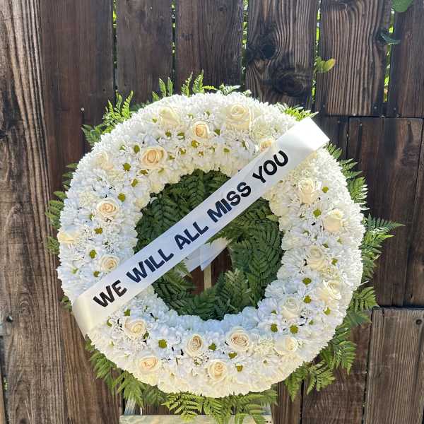 White funeral wreath on an easel with a memorial ribbon