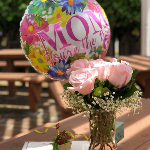 Pink roses in a glass vase with a floral Mother's Day balloon