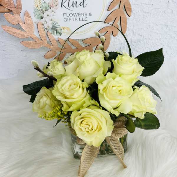 Pale yellow roses in a glass vase with a burlap bow