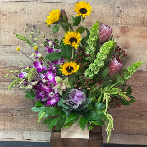 Mixed bouquet with sunflowers, purple orchids, and green blooms in a wooden box