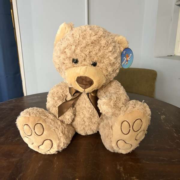 Plush teddy bear with a brown ribbon sitting on a table