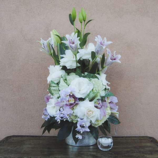 Tall white and lavender floral arrangement in a silver vase