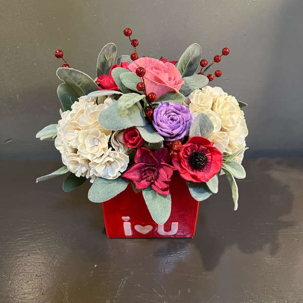 Bouquet of pink, red, purple, and cream flowers in a red vase