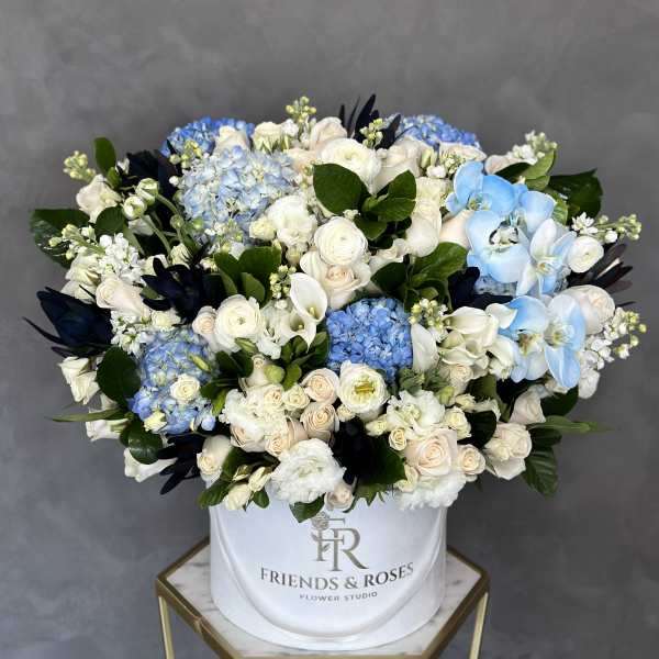 Large mixed bouquet of white, cream, and blue flowers in a white hatbox