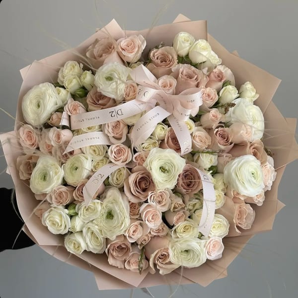 Large bouquet of blush and white roses wrapped in pale pink paper