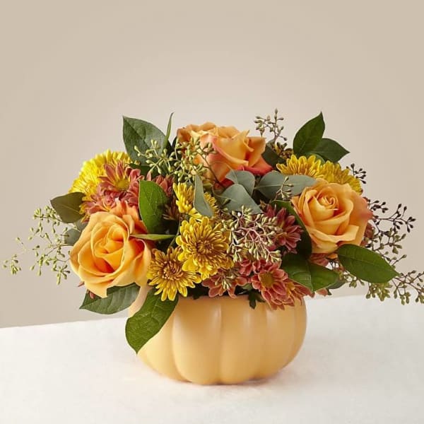 Orange roses and yellow mums in a pumpkin-shaped vase