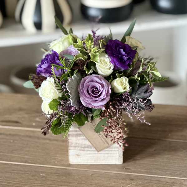 Bouquet of purple and white roses in a small square vase