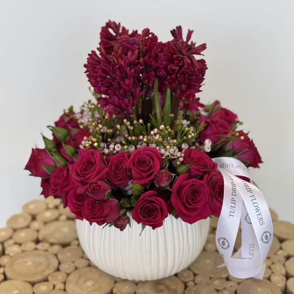 Magenta roses and dark pink blooms in a white ribbed vase