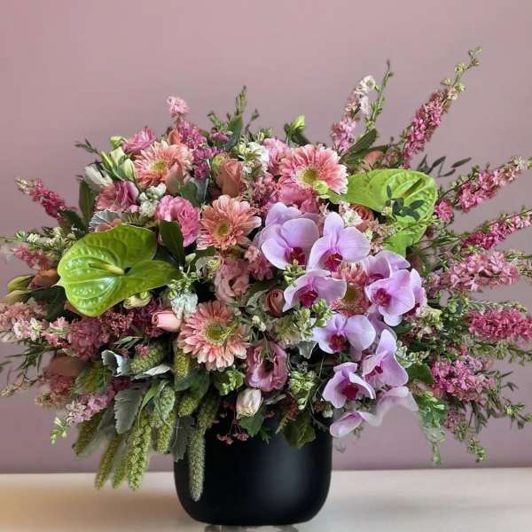 Pink mixed bouquet with orchids and gerbera daisies in a black vase