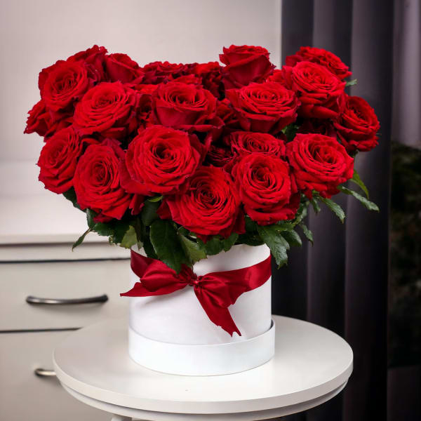 Red roses arranged in a white hat box with a red ribbon