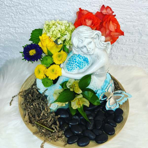 Floral arrangement with a white mermaid figurine, roses, and mixed blooms on a tray