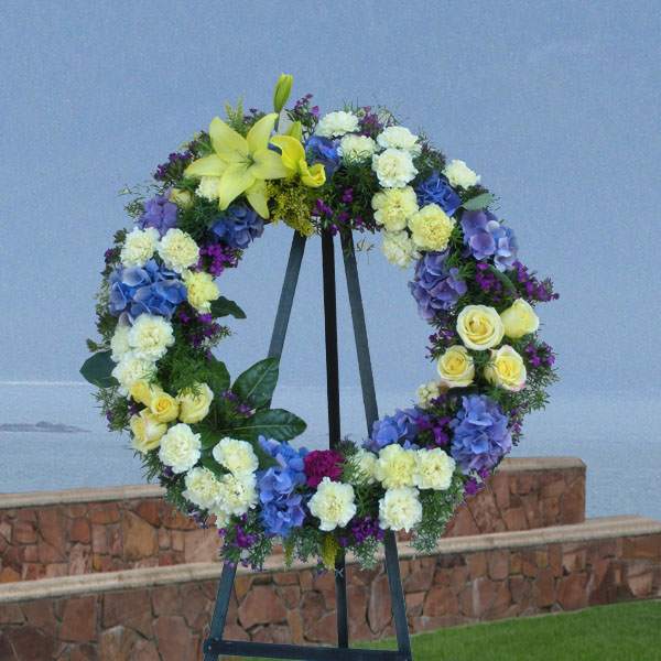 Large floral wreath on a black easel with yellow, blue, white, and purple flowers