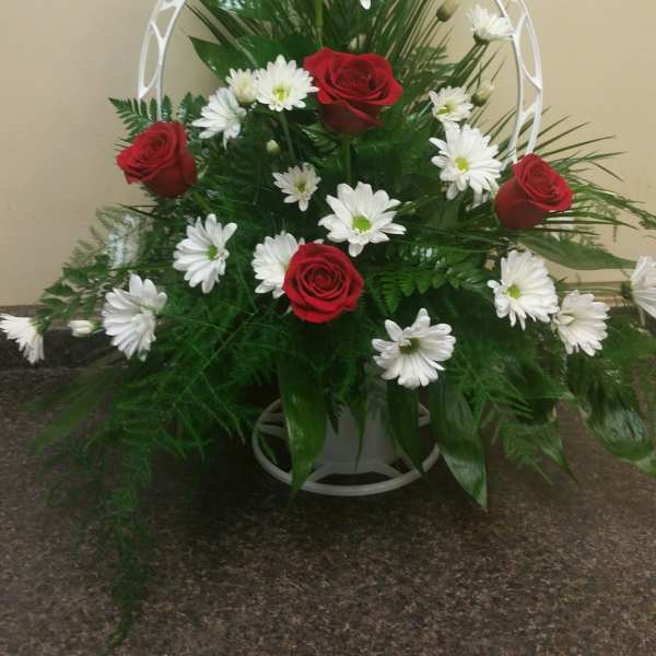 Red roses and white daisies arranged in a white standing frame