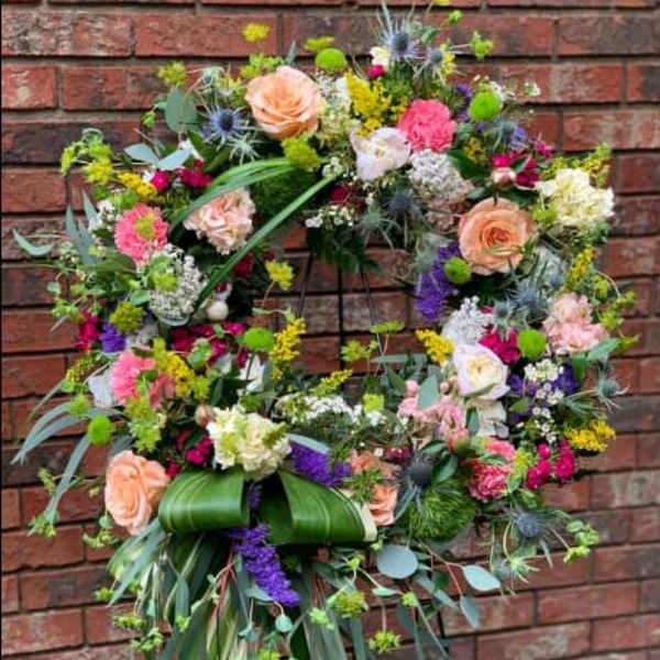 Large floral wreath with peach roses and mixed blooms on a stand