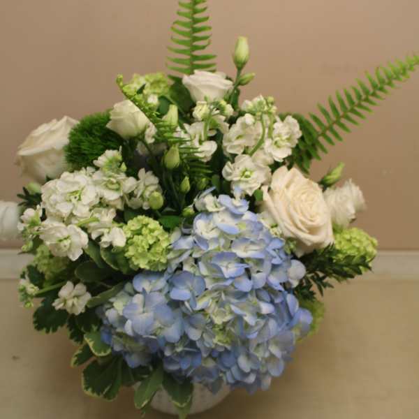 Blue hydrangeas and white roses arranged in a low vase