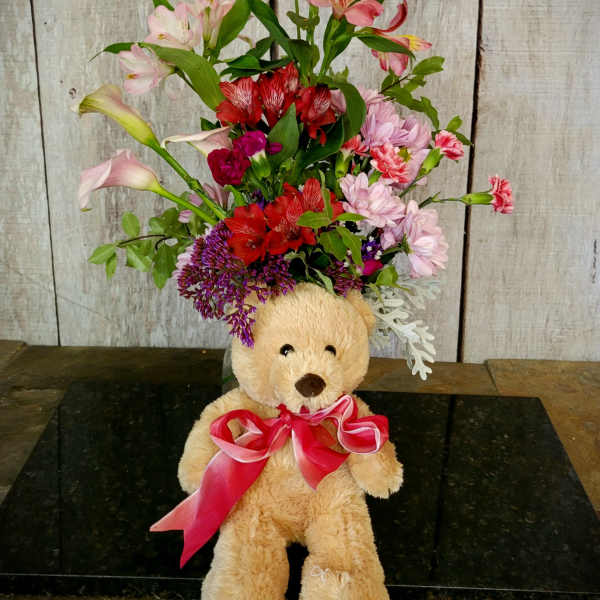 Teddy bear with a mixed flower arrangement and pink ribbon