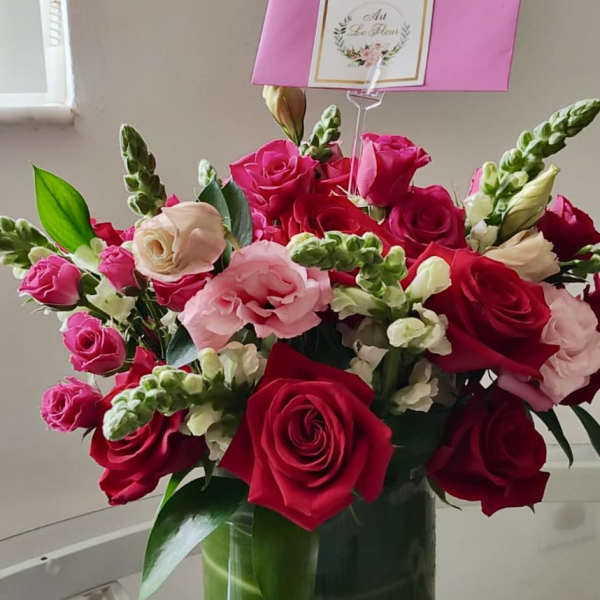 Pink and red roses with white snapdragons in a glass vase
