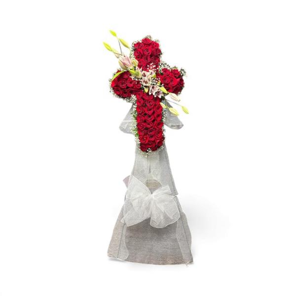 Cross-shaped arrangement of red roses with white lilies on a stand