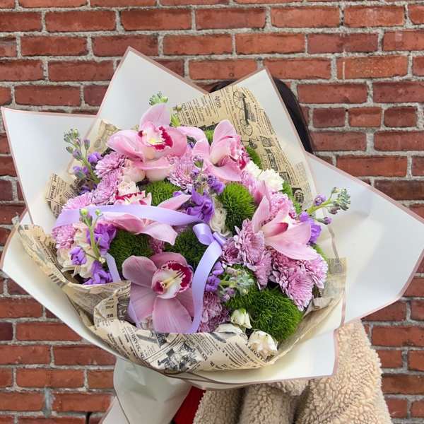 Large bouquet of pink orchids and purple flowers wrapped in paper