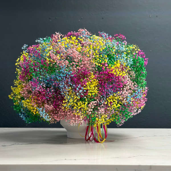 Large multicolored bouquet of tiny flowers in a white vase