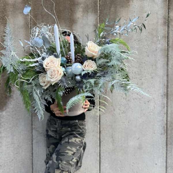 Large winter floral arrangement with white roses and candles in a container