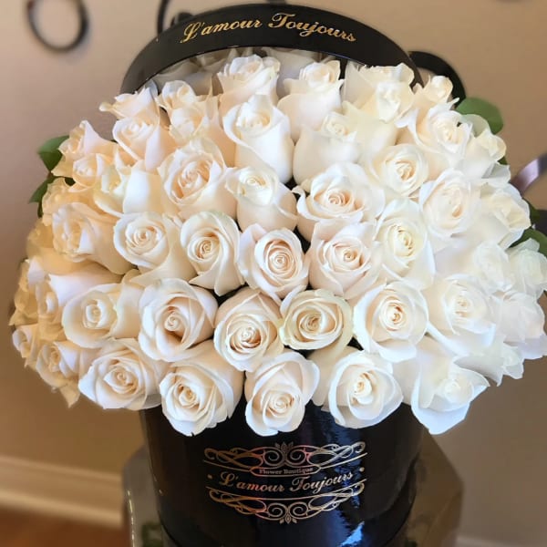 Round black hatbox filled with tightly packed cream white roses