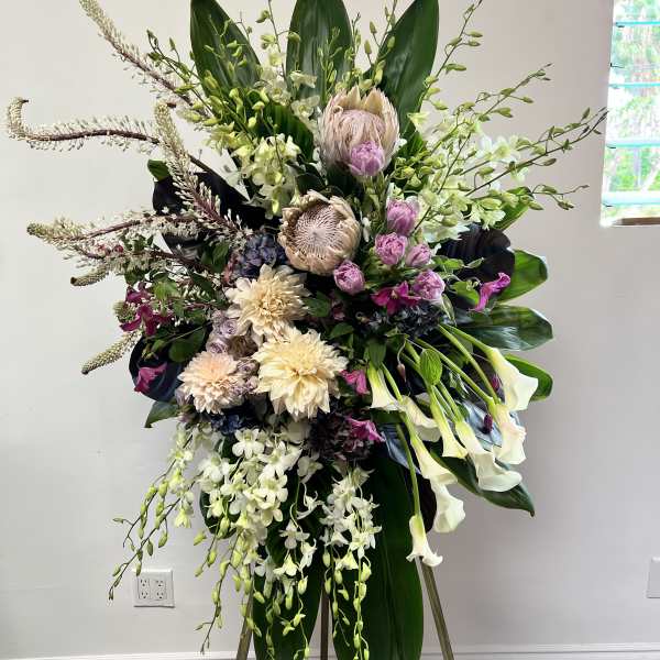 Tall floral standing spray with white orchids, calla lilies, and pink blooms