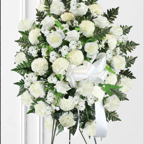 White rose and carnation standing spray with a white ribbon