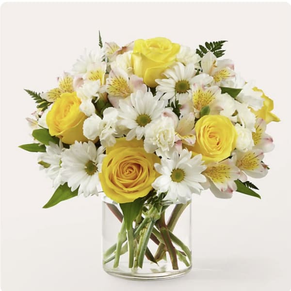 Yellow roses and white daisies in a clear glass vase