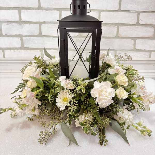 White floral wreath around a black lantern with a candle inside