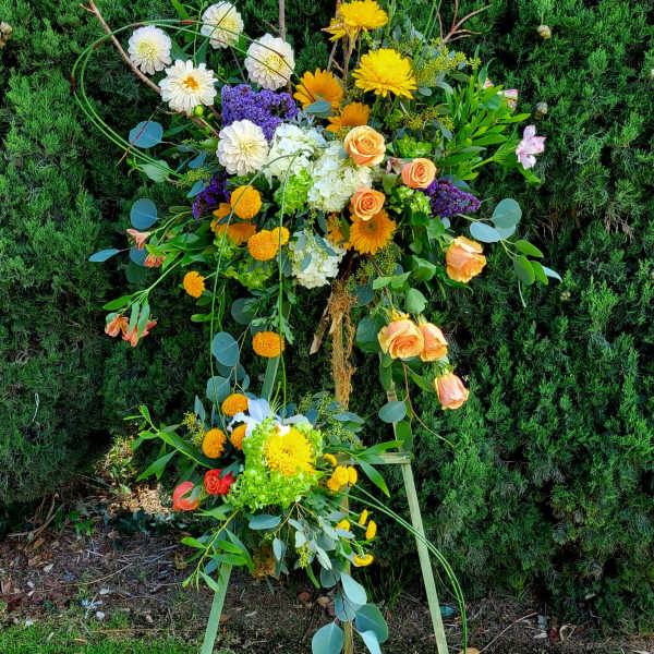 Large floral standing spray with yellow, white, orange, and purple blooms
