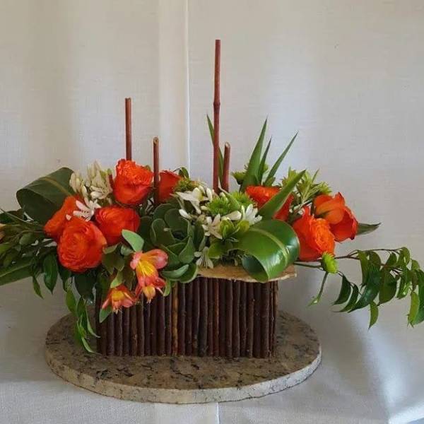 Orange roses arranged in a low rectangular centerpiece with greenery