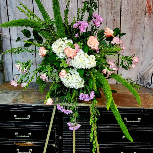Large floral spray with pink roses, white hydrangeas, and purple blooms