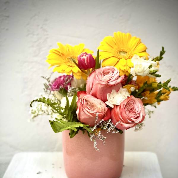 Pink roses and yellow gerbera daisies in a blush vase