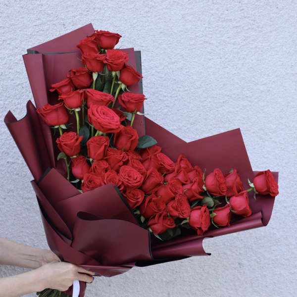 Bouquet of red roses wrapped in burgundy paper
