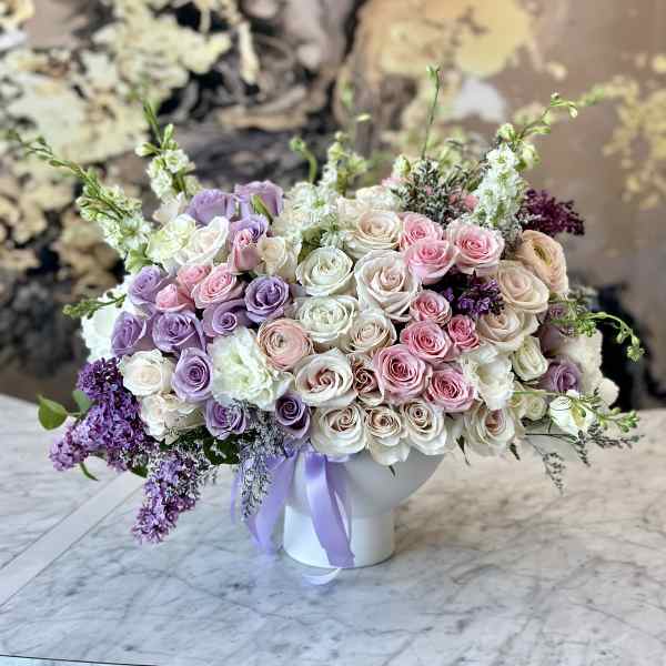 Large bouquet of pink, white, and lavender roses in a white vase