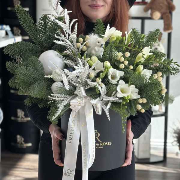 Winter bouquet with white flowers, pine branches, and a small teddy bear