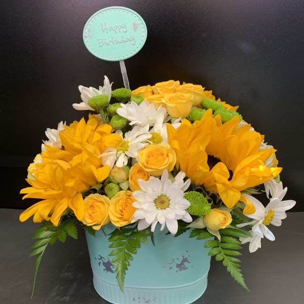 Yellow roses and white daisies in a turquoise birthday container