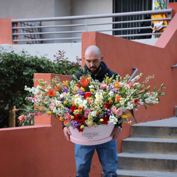 Large mixed flower arrangement in a pink hat box