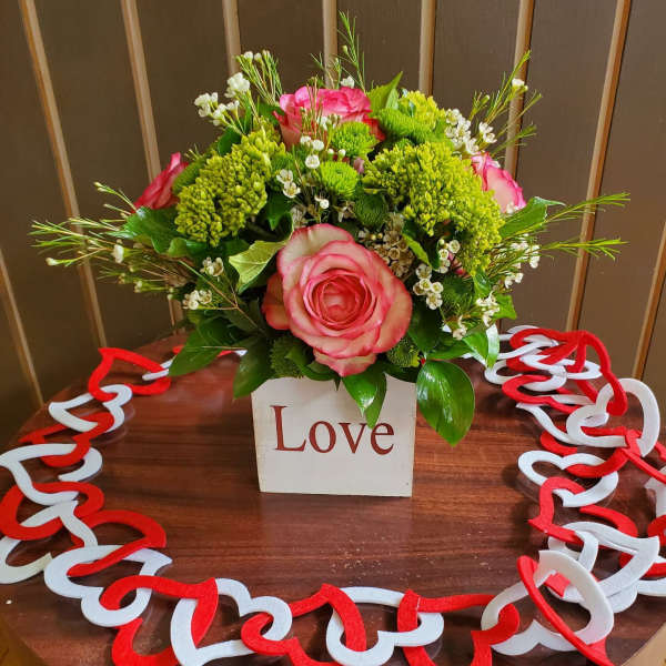 Pink roses and green chrysanthemums in a white box with a heart garland