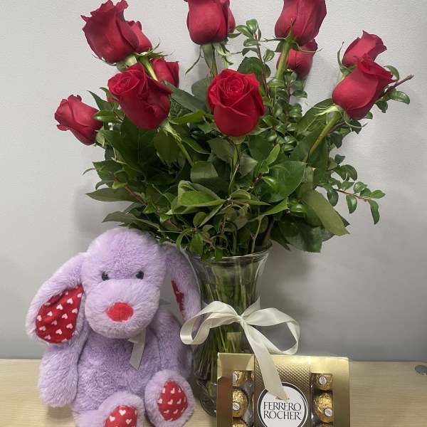 Red roses in a glass vase with a plush purple bunny and Ferrero Rocher chocolates